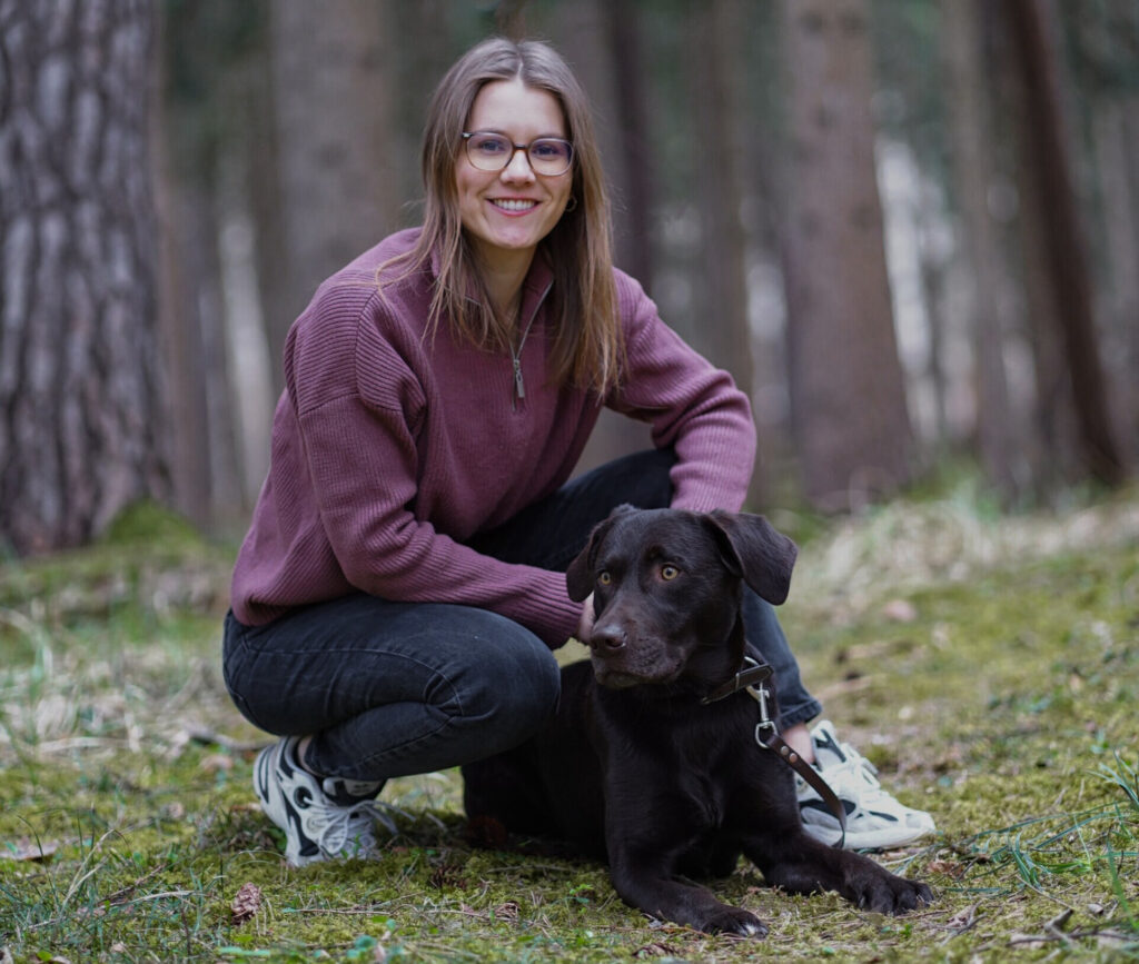 Besitzerin mit angelehntem Hund im Wald